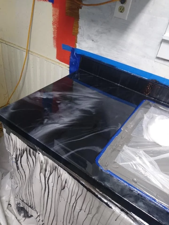 Dark patterned countertop beside a masked kitchen sink