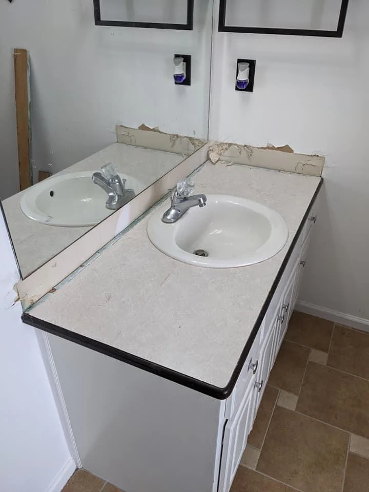 Bathroom vanity with a light countertop and exposed wall surface